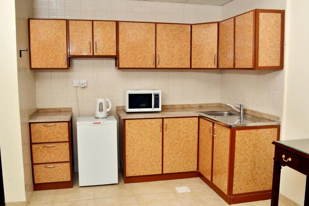 a kitchen with a white refrigerator and a microwave at Sara Hotel Apartments in Ajman 