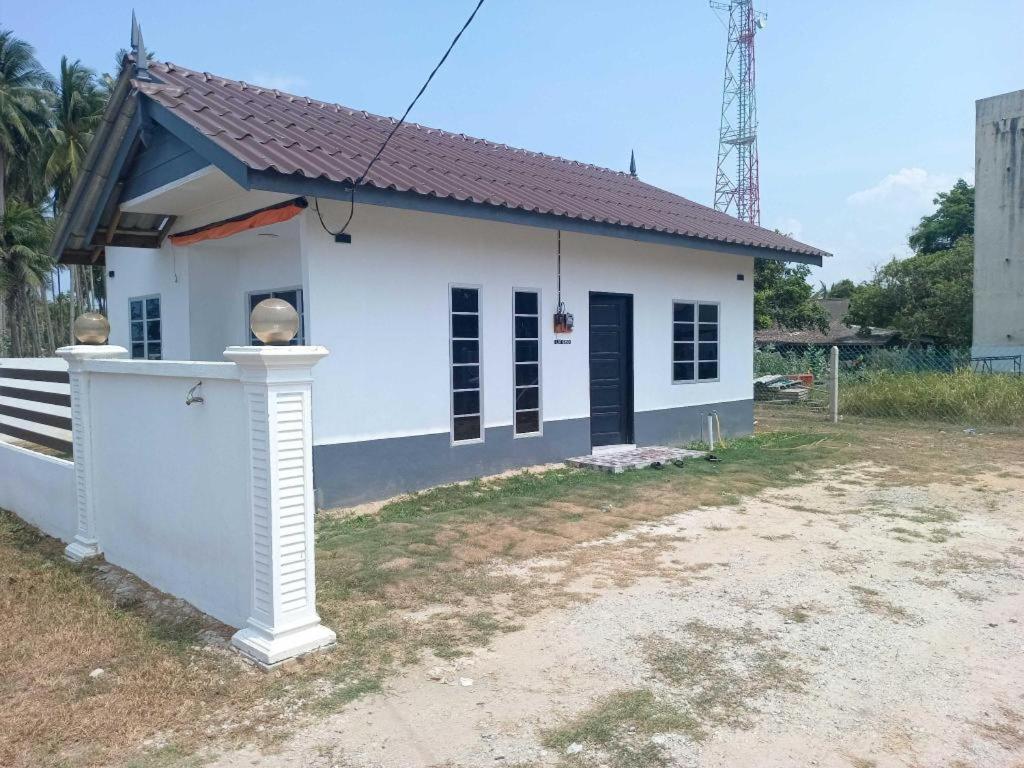 a small white house with a black door at OYO 90976 Pantaistay@baturakit in Kuala Terengganu