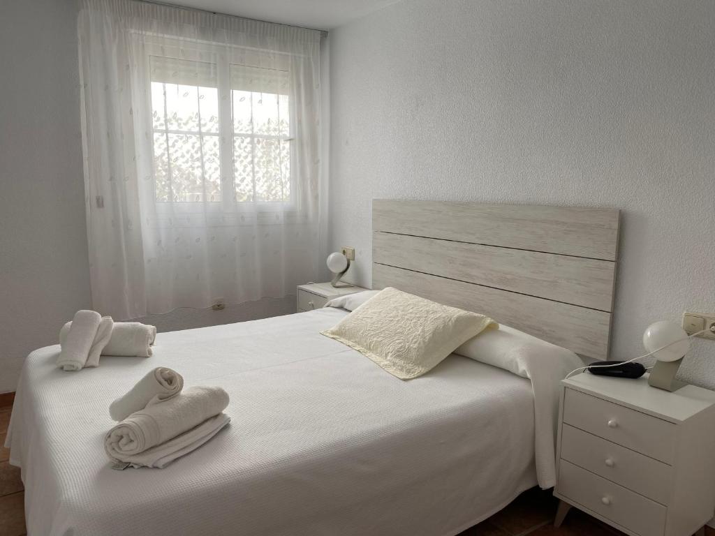 a bedroom with a white bed with towels on it at Apartahotel Vistamar San José in San José