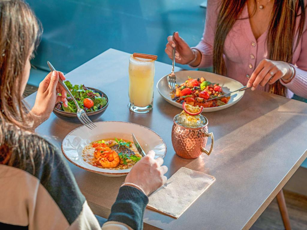 a group of people sitting at a table with plates of food at Mercure Lisboa Almada in Almada