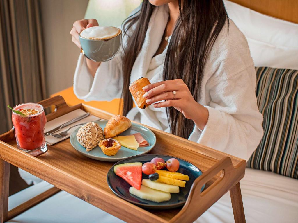 a woman sitting at a table with a plate of food at Mercure Lisboa Almada in Almada