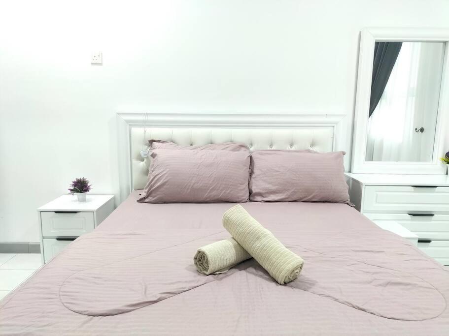 a white bedroom with a large bed with pink sheets at Meraki Homestay Ladang Tanjung in Kuala Terengganu