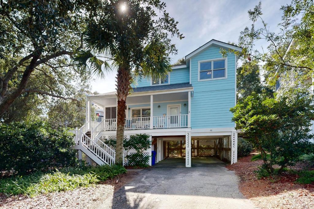 a blue house with a palm tree in front of it at Pelican Bay 46 in Isle of Palms