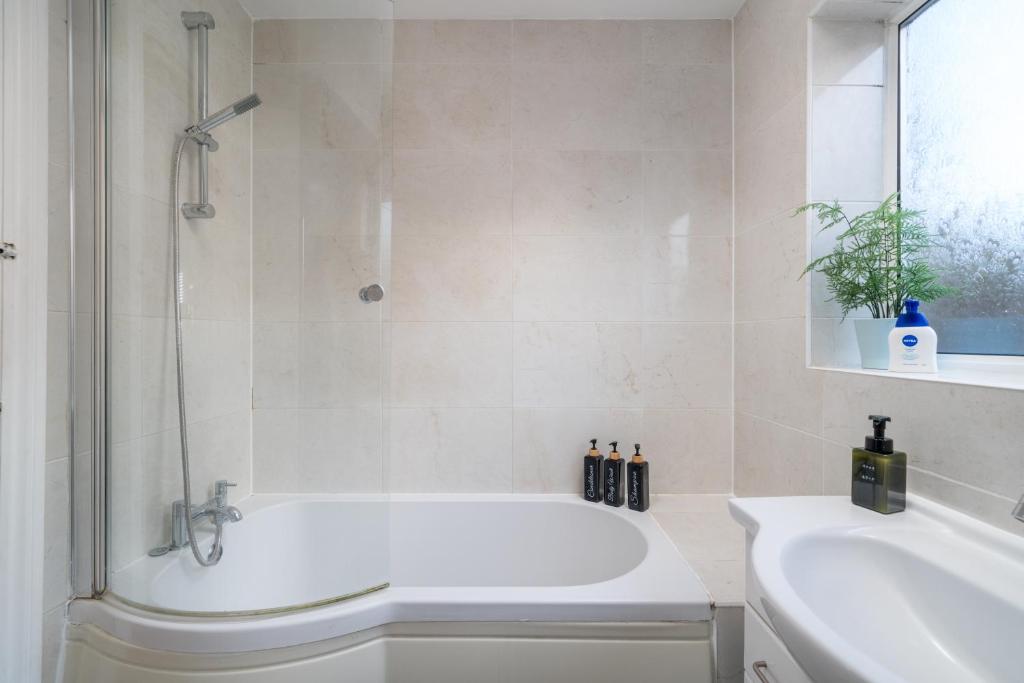 ein weißes Badezimmer mit Badewanne und Waschbecken in der Unterkunft Madika Homes - Contractor Stays near Edgware Tube Station with Free Parking in Edgware