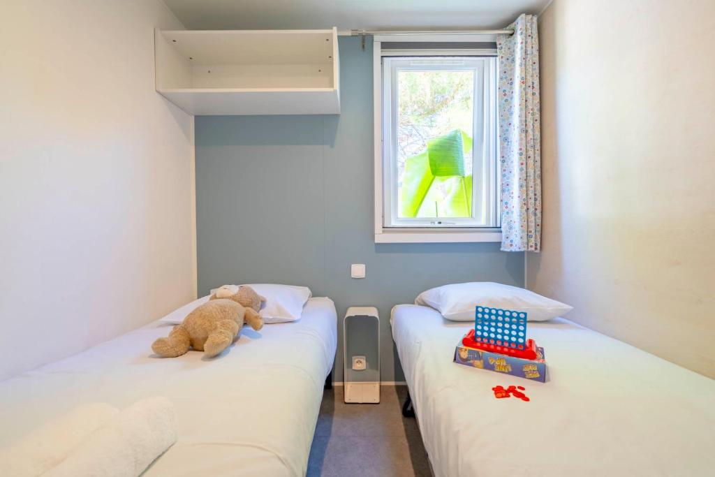 two beds in a room with a teddy bear on the bed at Camping Paradis 4 étoiles A La Corniche La Rochelle Angoulins in Angoulins-sur-Mer