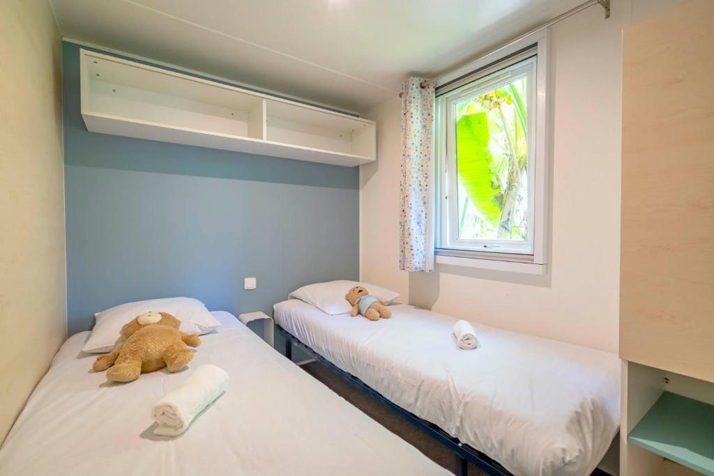 two beds in a room with two teddy bears on them at Camping Paradis 4 étoiles A La Corniche La Rochelle Angoulins in Angoulins-sur-Mer