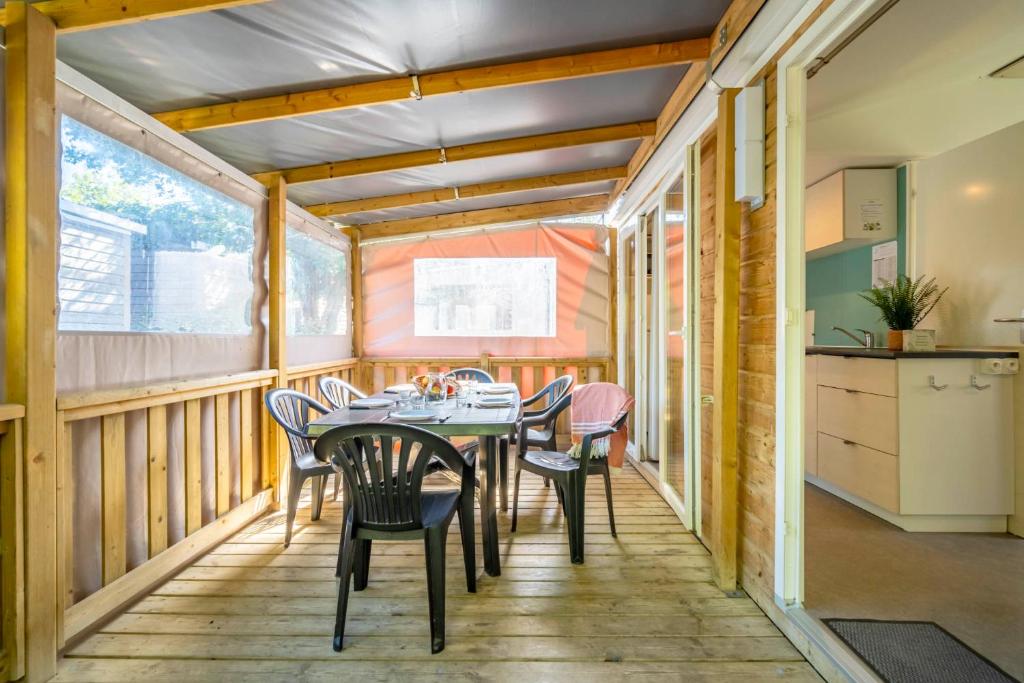 a dining room with a table and chairs on a deck at Camping Paradis 4 étoiles A La Corniche La Rochelle Angoulins in Angoulins-sur-Mer