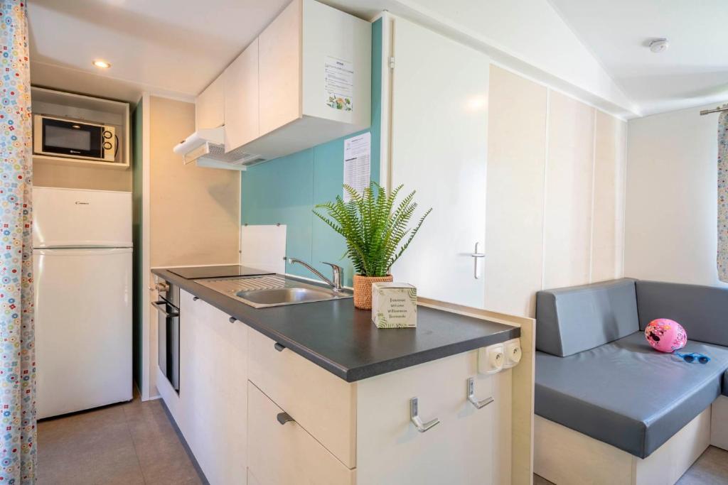 a small kitchen with a sink and a refrigerator at Camping Paradis 4 étoiles A La Corniche La Rochelle Angoulins in Angoulins-sur-Mer