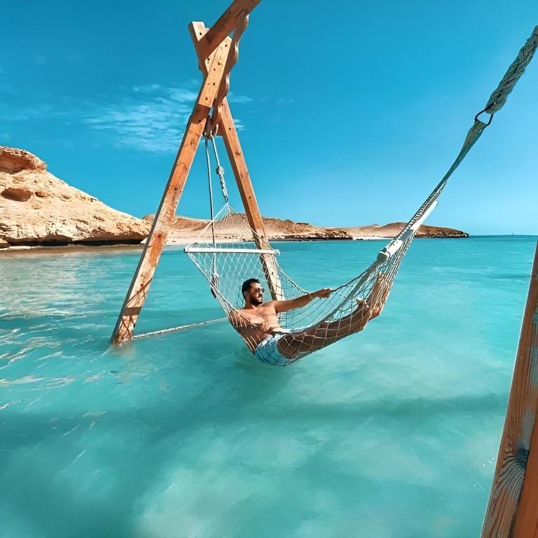 a man laying in a hammock in the water at Al-Dora Resort Hurghada in Hurghada