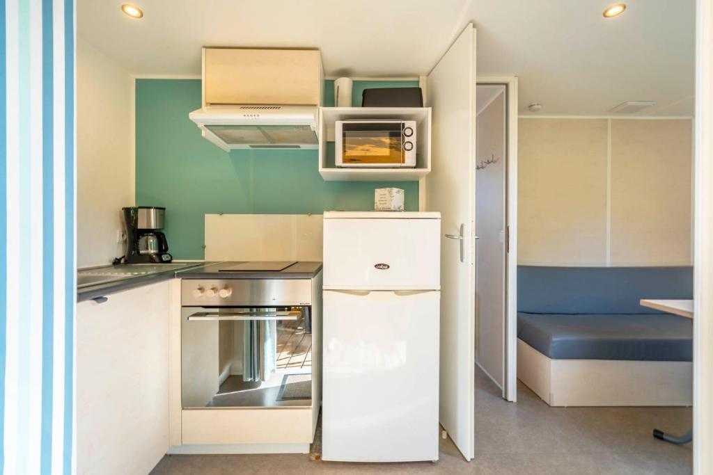 a small kitchen with a stove and a refrigerator at Camping Paradis 4 étoiles A La Corniche La Rochelle Angoulins in Angoulins-sur-Mer
