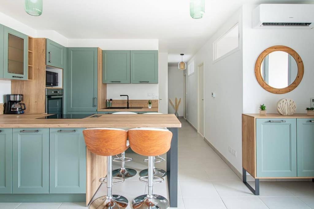 a kitchen with blue cabinets and a counter with stools at Le Bohème Classé 3 étoiles in La Londe-les-Maures
