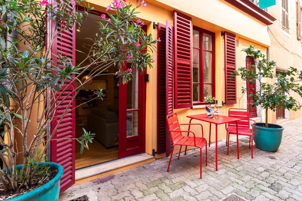 d'une terrasse avec des portes rouges, une table et des chaises. dans l'établissement COSY VOLTI AP4434 By Riviera Holiday Homes, à Villefranche-sur-Mer