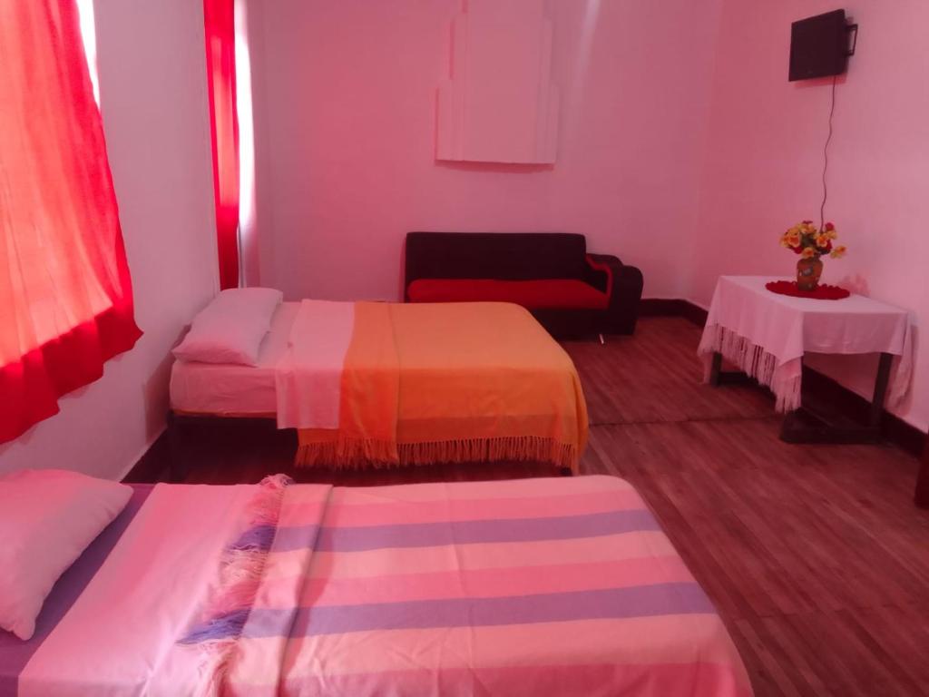 a living room with two beds and a couch at Nuevo Hostal Victoria in Quito