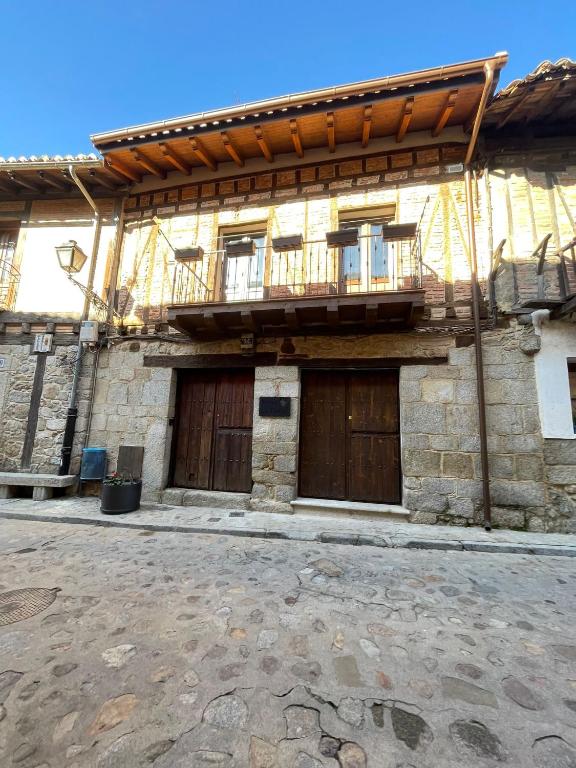 an old stone building with two doors and a balcony at Casa La tranca in Cuevas del Valle