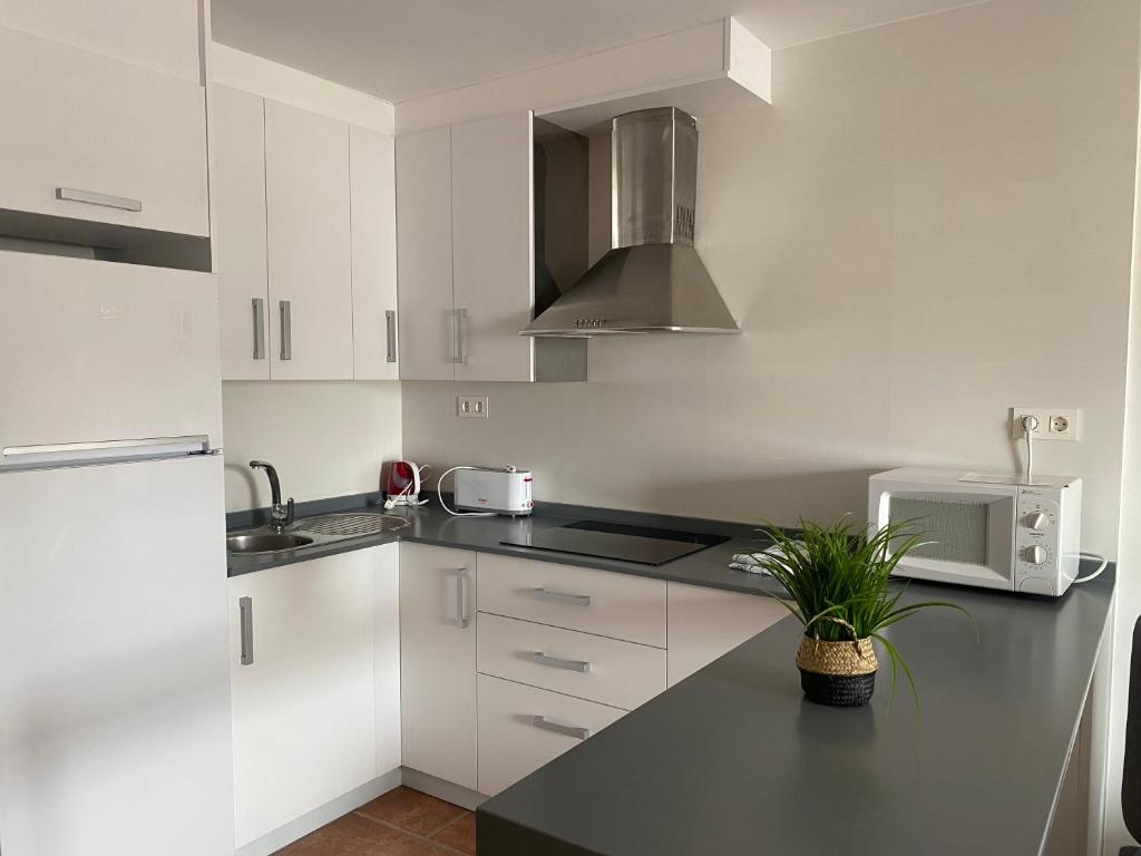 a kitchen with white cabinets and a black counter top at Apartahotel Vistamar San José in San José