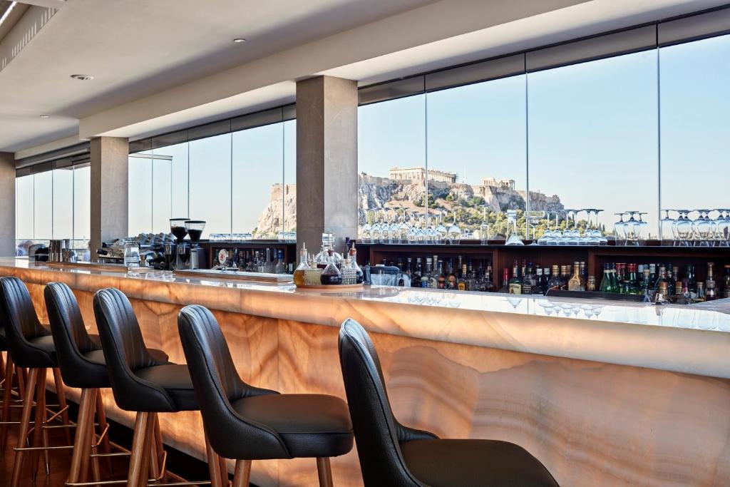 a bar with chairs and a view of the mountain at Electra Metropolis in Athens