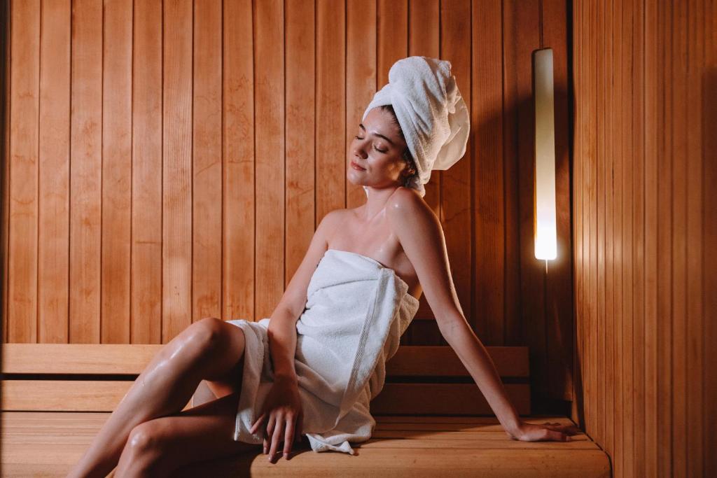a woman sitting in a sauna with a towel on her head at Electra Metropolis in Athens
