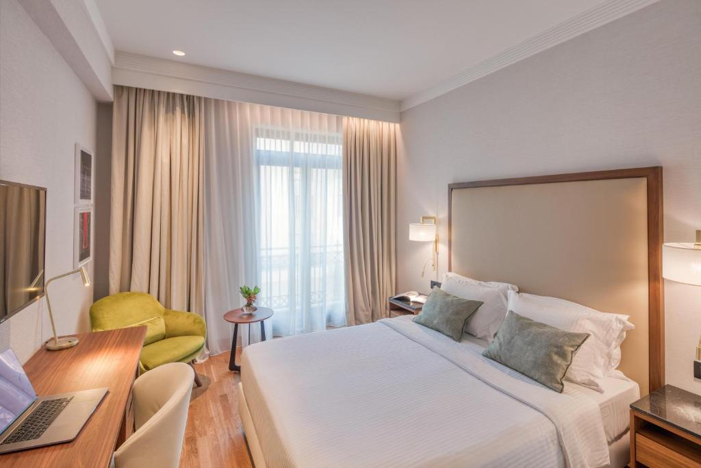 a hotel room with a bed and a desk with a laptop at Electra Palace Thessaloniki in Thessaloniki