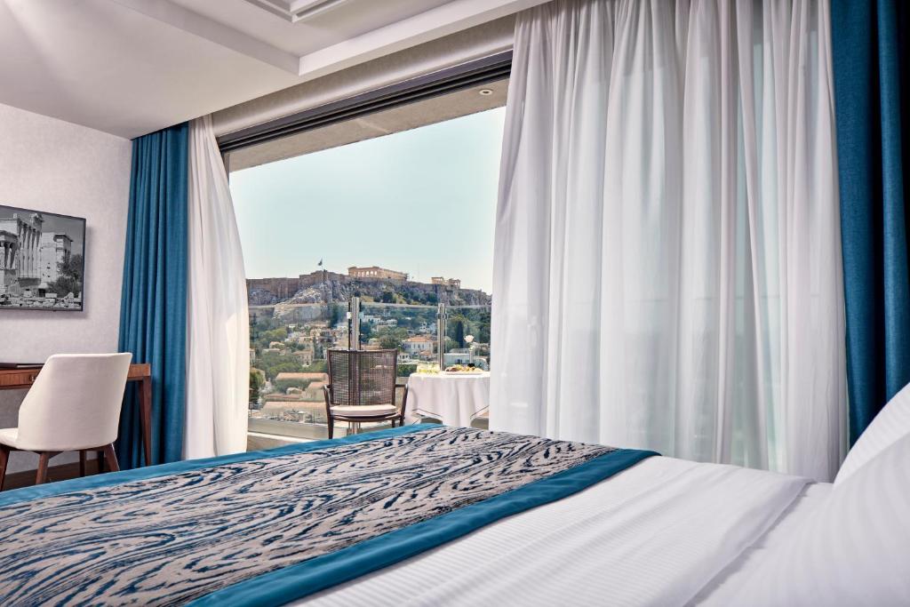 a bedroom with a bed and a large window at Electra Metropolis in Athens