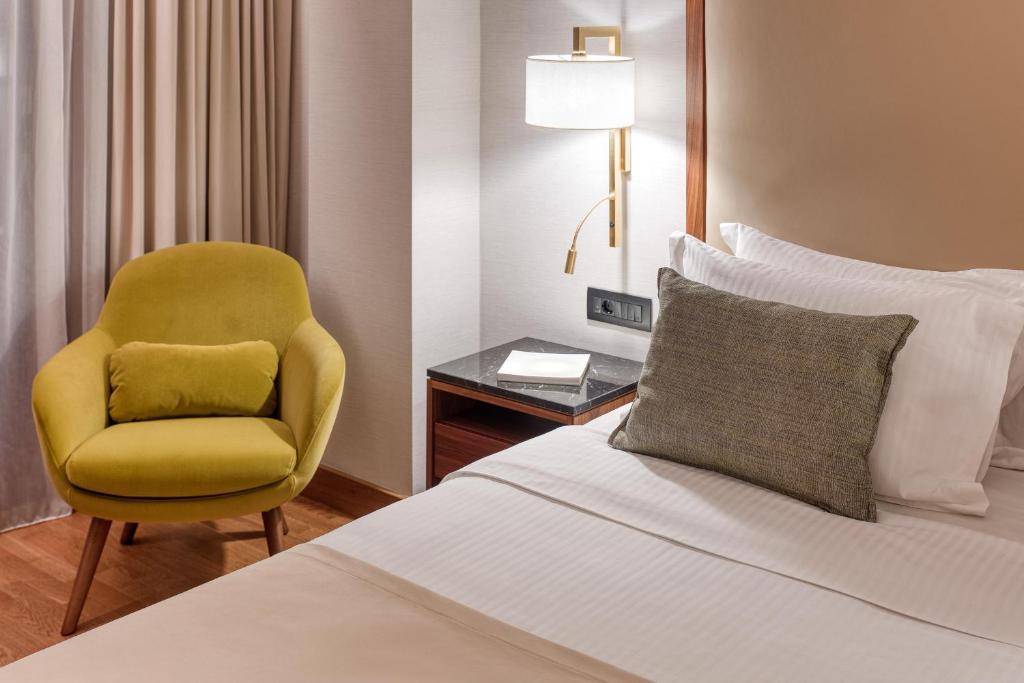 a hotel room with a bed and a yellow chair at Electra Palace Thessaloniki in Thessaloniki