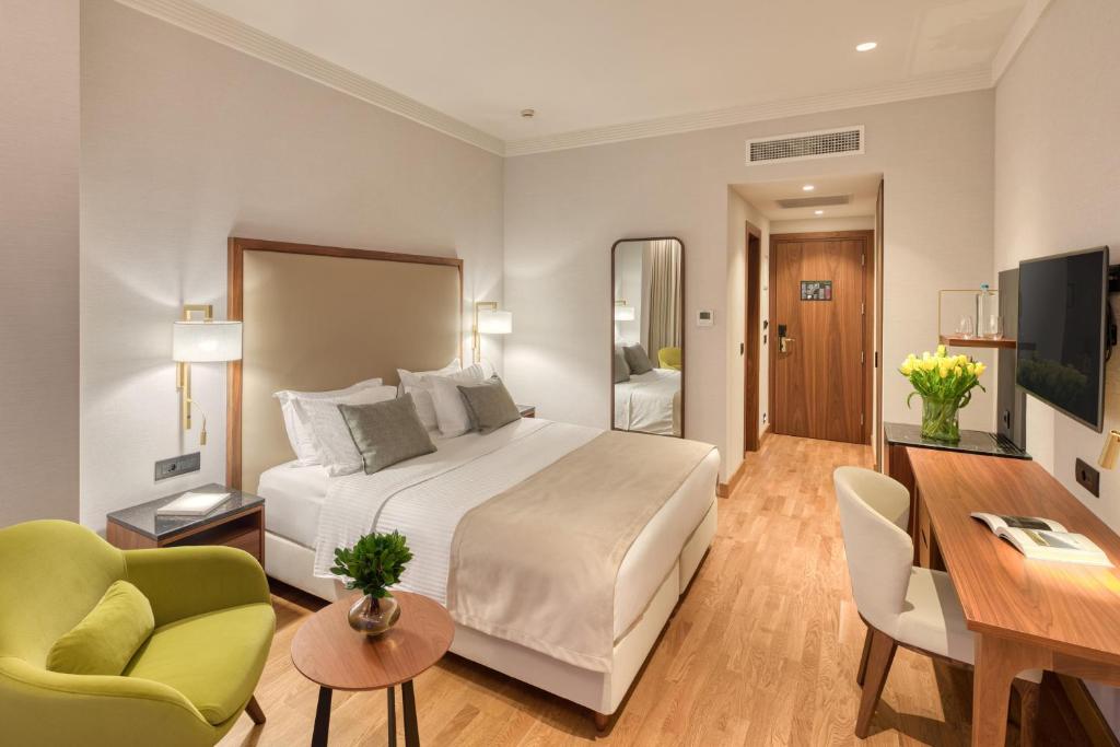 a hotel room with a bed and a desk and chairs at Electra Palace Thessaloniki in Thessaloniki