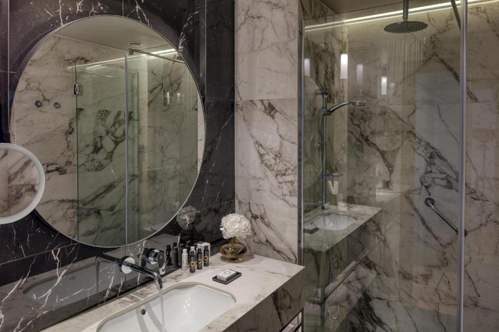 a bathroom with a shower and a sink and a mirror at Electra Palace Thessaloniki in Thessaloniki