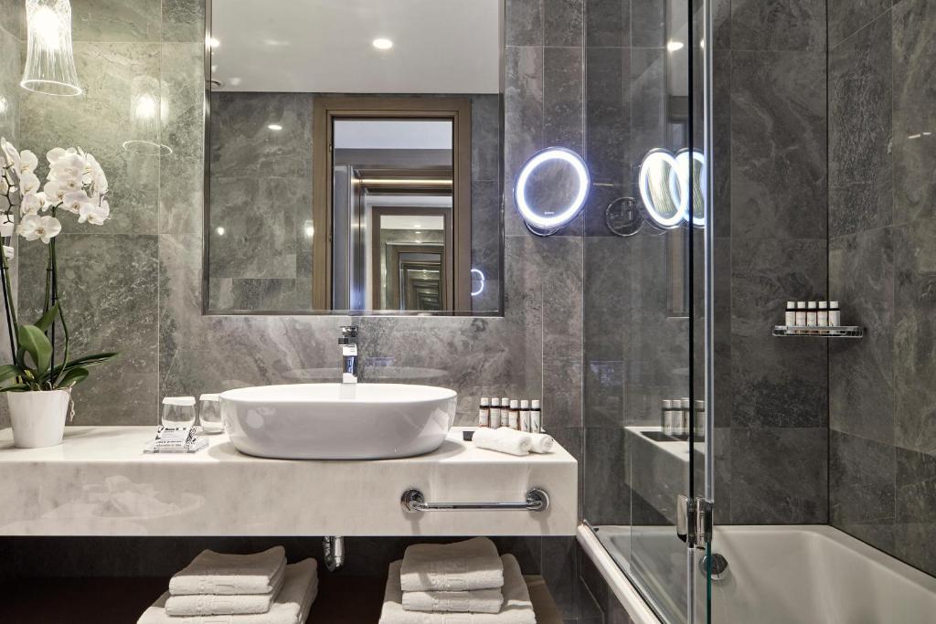a bathroom with a sink and a mirror and a tub at Electra Metropolis in Athens