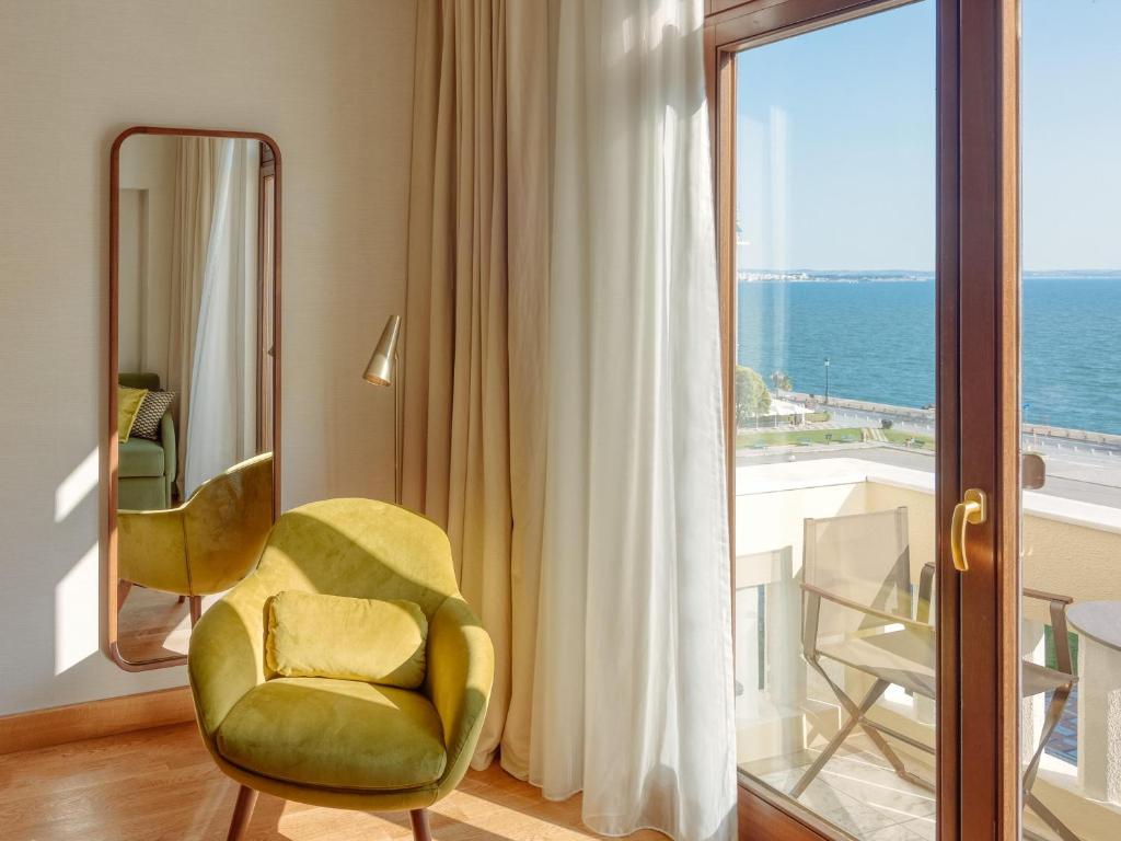 a living room with a yellow chair and a window at Electra Palace Thessaloniki in Thessaloniki