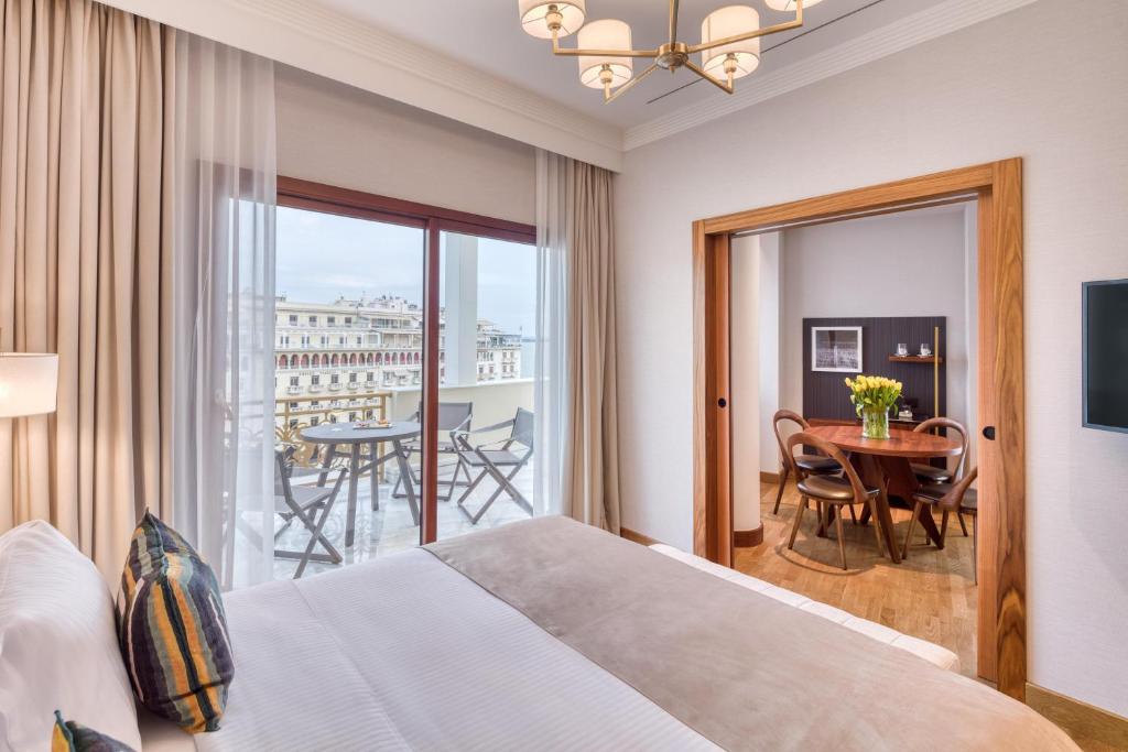 a bedroom with a bed and a balcony with a table at Electra Palace Thessaloniki in Thessaloniki