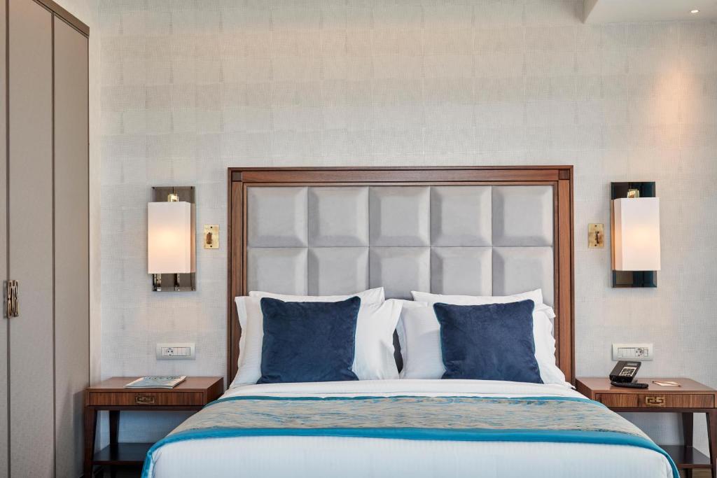 a bedroom with a large bed with blue pillows at Electra Metropolis in Athens