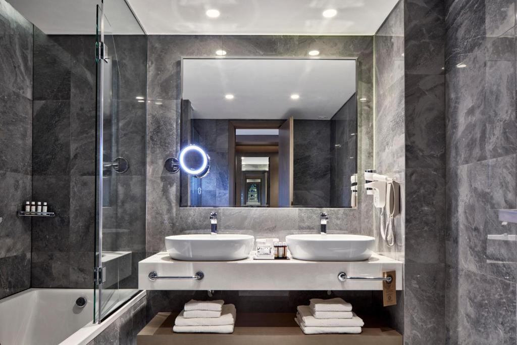 a bathroom with two sinks and a mirror and a tub at Electra Metropolis in Athens