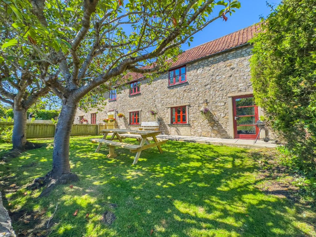 a wooden picnic table in front of a stone building at Seaside-Dog Friendly-Country Cottage-w log burner in Worle