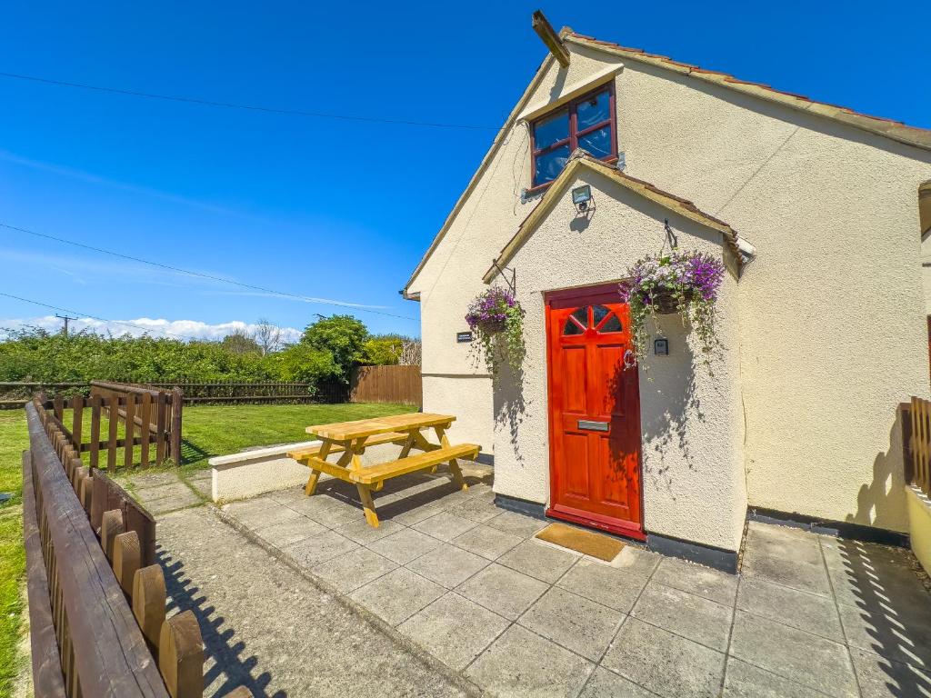 a house with a red door and a picnic table at Snug, Dog Friendly, Country Cottage in Worle