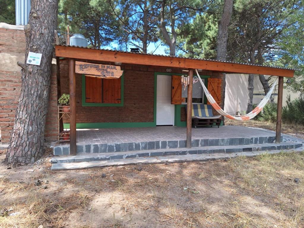 a small house with a hammock in front of a tree at Casa Monte hermoso Barrio las Dunas in Monte Hermoso