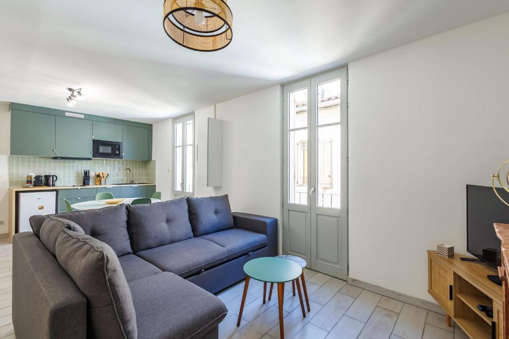 un salon avec un canapé bleu et une table dans l'établissement Appartement Sureau - Welkeys, à Avignon