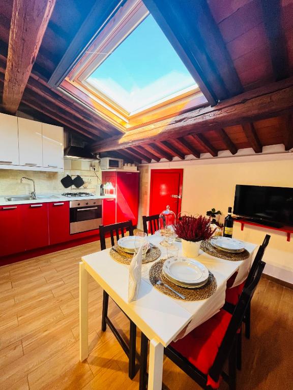 a kitchen with a table with chairs and red cabinets at Mansarda nel Cuore di Pisa in Pisa