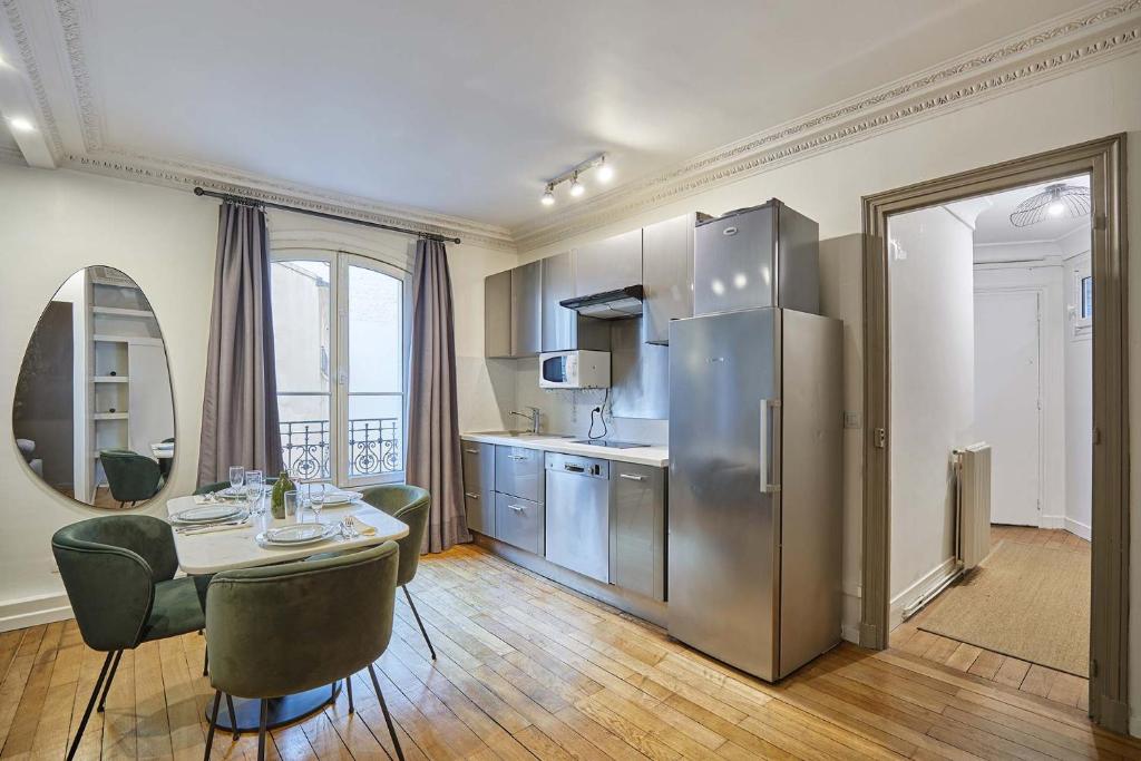 une cuisine avec une table et un réfrigérateur en acier inoxydable dans l'établissement Charming Apartment Center of Paris by Studio Prestige, à Paris