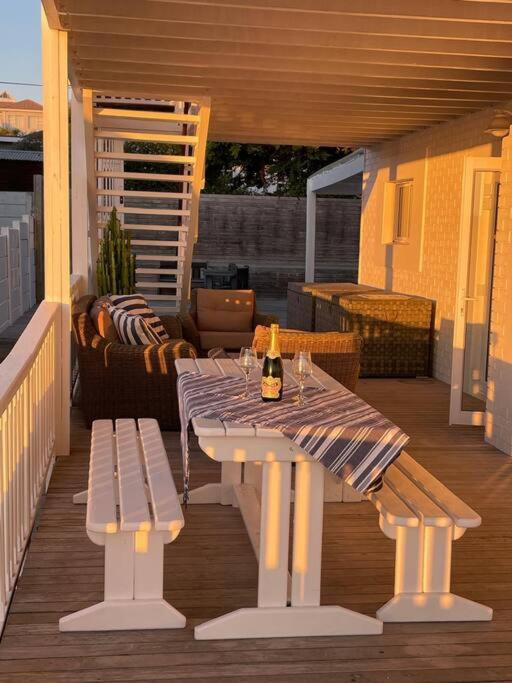 a patio with a table and benches on a deck at Dasseneiland Apartment Yzerfontein in Yzerfontein