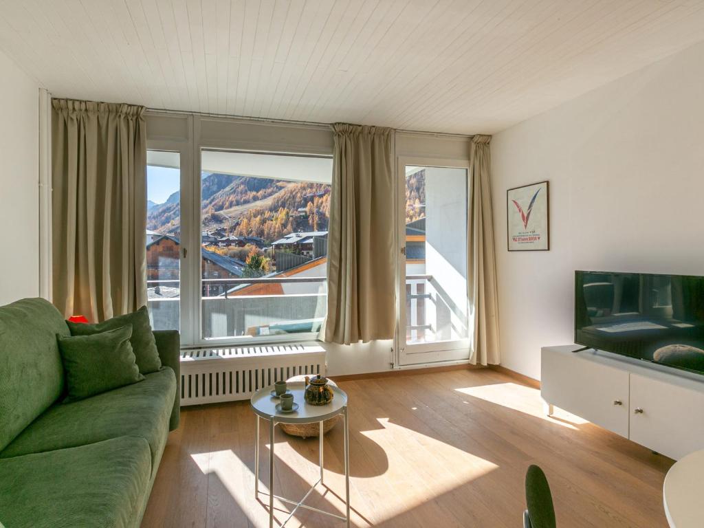 - un salon avec un canapé vert et une grande fenêtre dans l'établissement Studio cosy pour 4 avec balcon et wifi à Val-d'Isère - FR-1-694-364, à Val dʼIsère