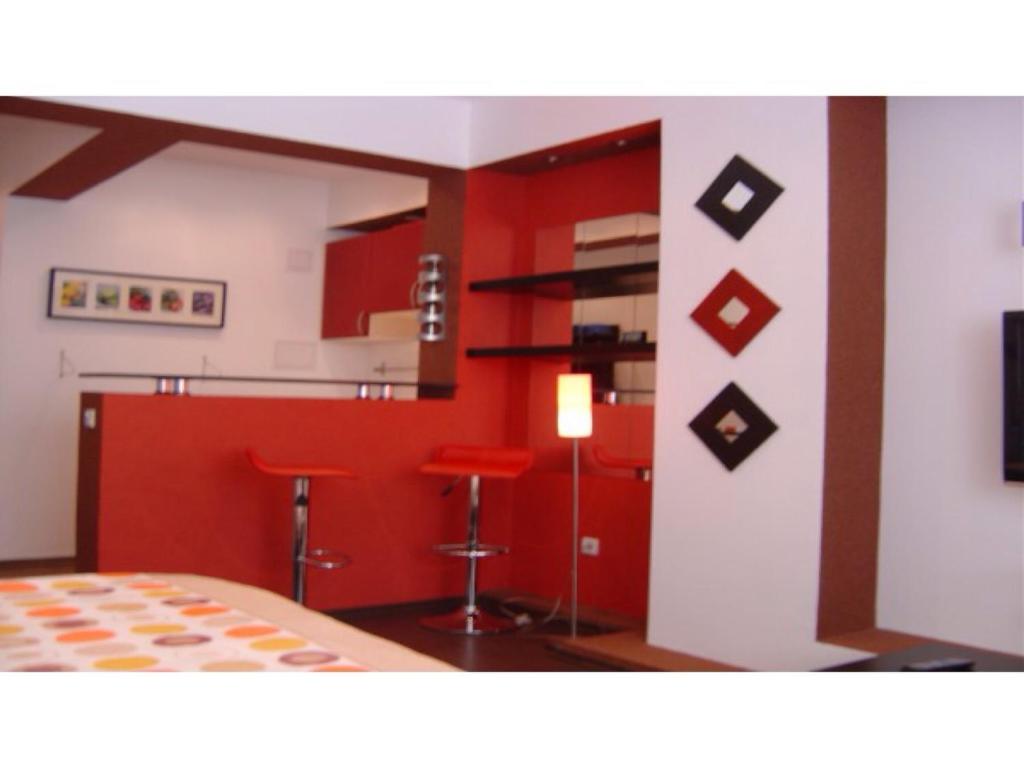 a bedroom with red walls and a kitchen with stools at Studio Cismigiu Park in Bucharest