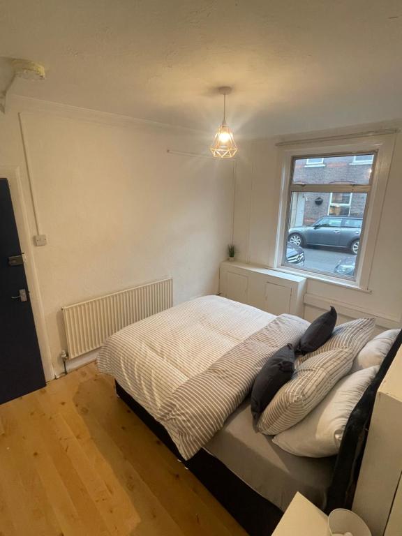 a bedroom with a bed with pillows and a window at Close to Central in Luton