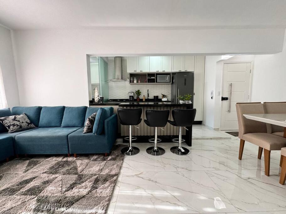 uma sala de estar com um sofá azul e uma cozinha em Apartamento da Jessie em Poços de Caldas em Poços de Caldas