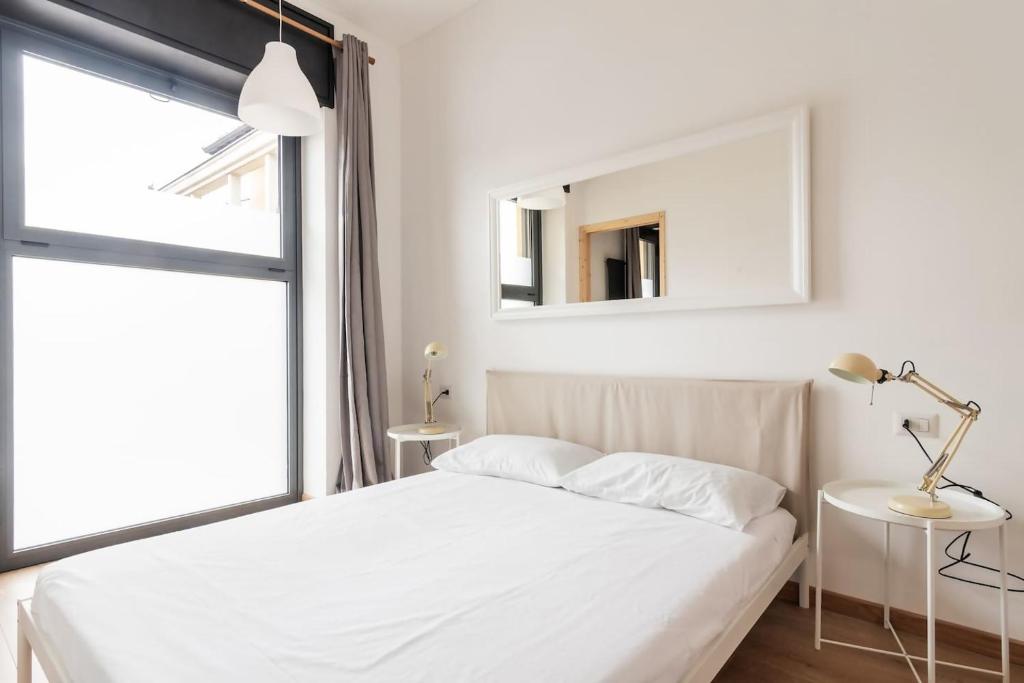 une chambre blanche avec un lit et un miroir dans l'établissement AirLoft 2 confort vicino a Rho Fiera, à Rho