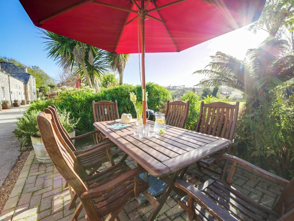 a wooden table with a red umbrella on a patio at Turtle Cottage in Charlestown