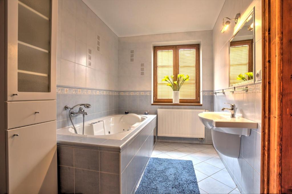 a white bathroom with a tub and a sink at Penzión Grobský Dvor in Slovenský Grob