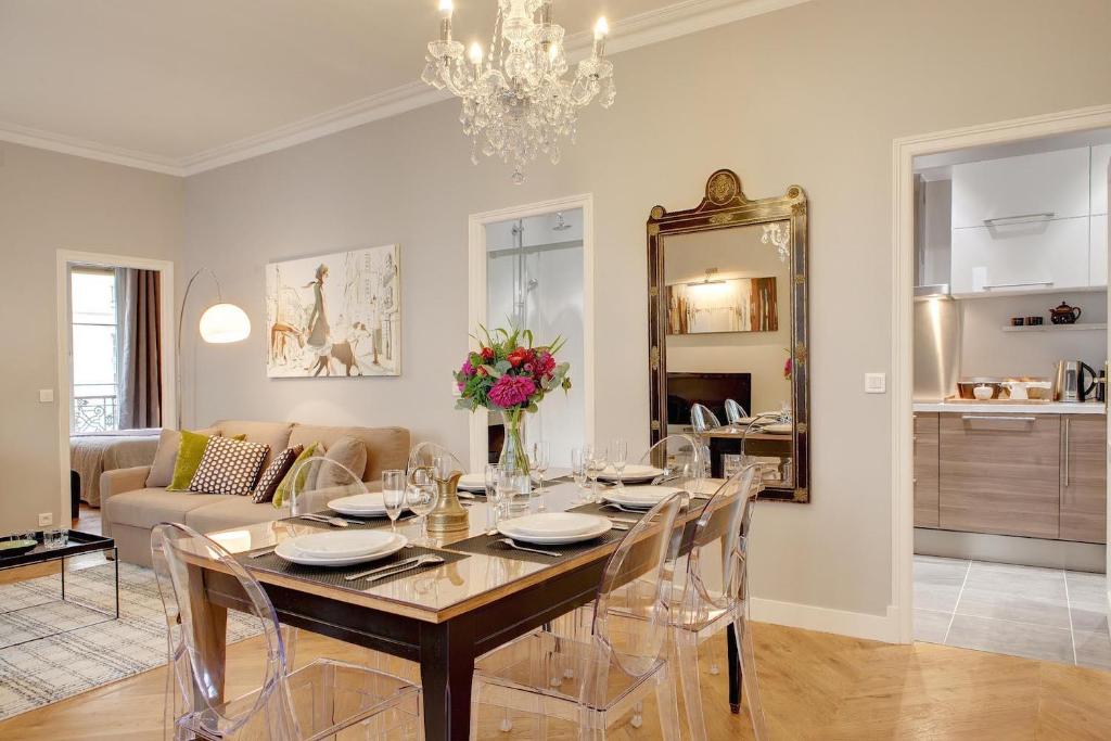 - une salle à manger avec une table, des chaises et un miroir dans l'établissement Blanc Manteau Residence, à Paris
