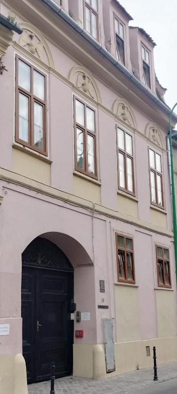 a large white building with a black door at Casa Sforii Brasov in Braşov