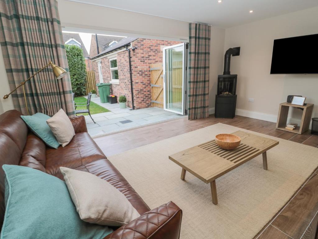 Una sala de estar con un sofá de cuero y una mesa. en Breamish, en Alnwick