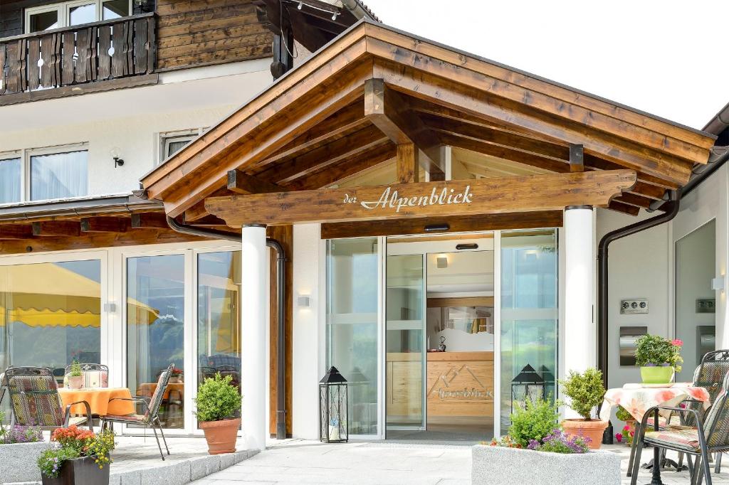 a restaurant with a wooden roof and glass doors at Hotel Alpenblick in Fischen