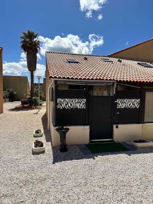 une maison avec une porte noire et un palmier dans l'établissement Coup de coeur au bord du lac, à Leucate-Plage